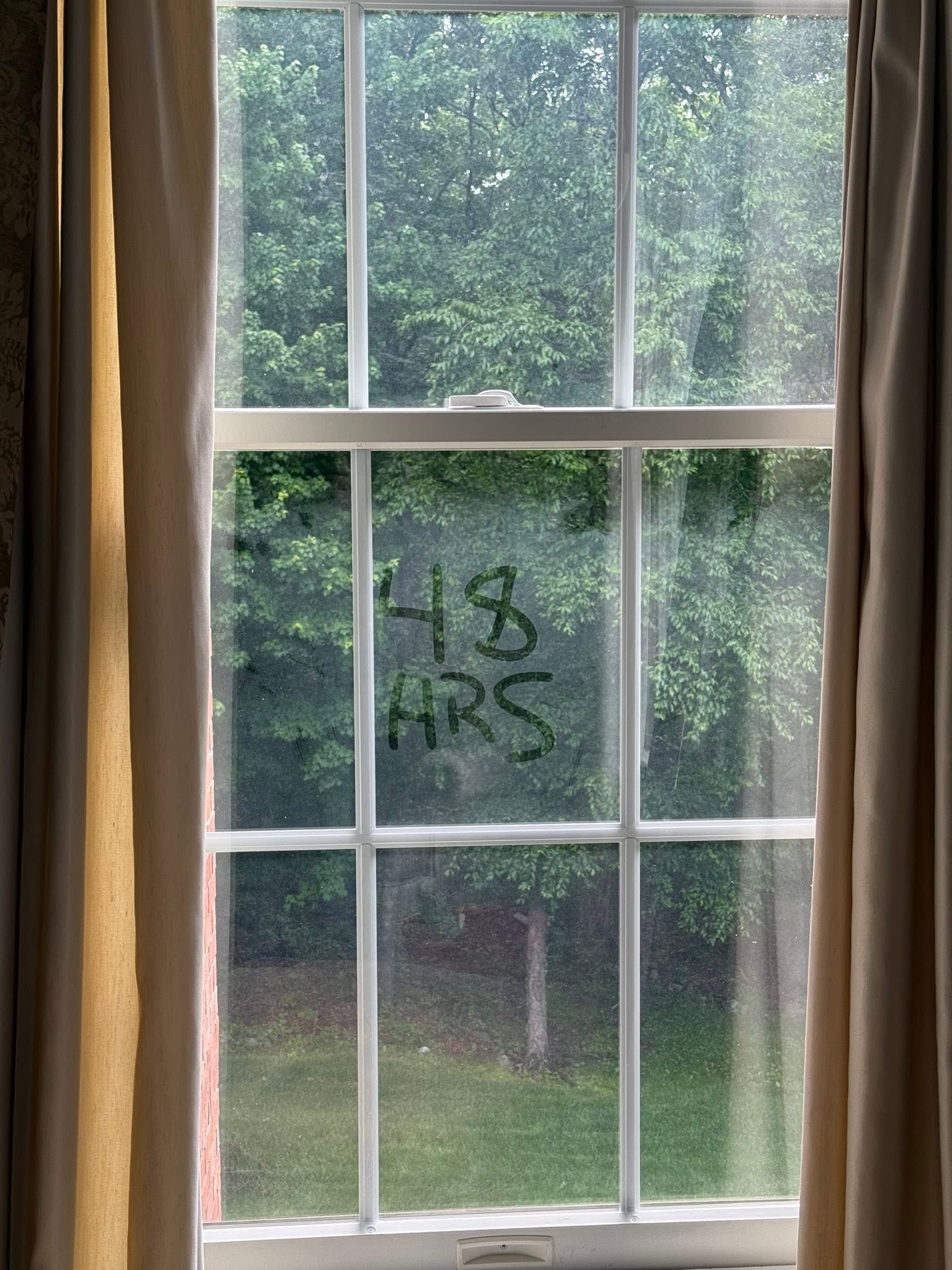 Hazy, streaked window before cleaning, with 48 HRS written on the glass