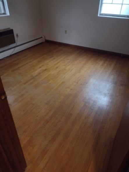 The same bedroom after cleanout, empty with a clean hardwood floor